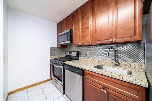 kitchen with light stone counters, baseboards, a sink, stainless steel appliances, and tasteful backsplash