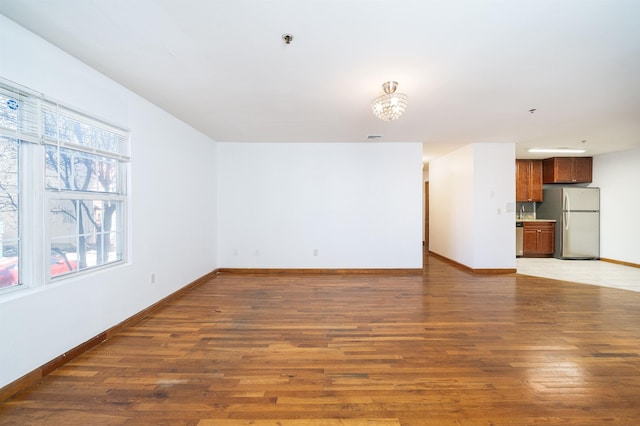 unfurnished living room with light wood finished floors, visible vents, and baseboards