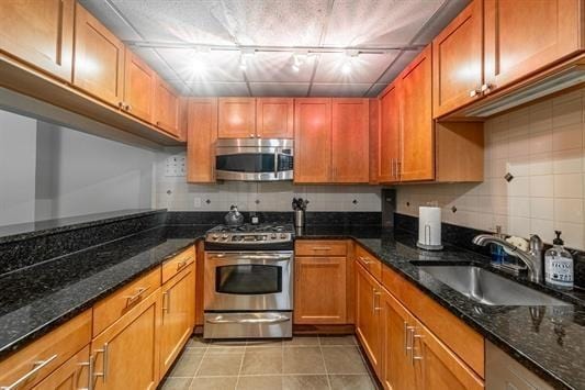 347 Varick St Unit 419A, Jersey City, NJ 07302 - kitchen featuring appliances with stainless steel finishes, a sink, tasteful backsplash, light tile patterned flooring, and dark stone countertops