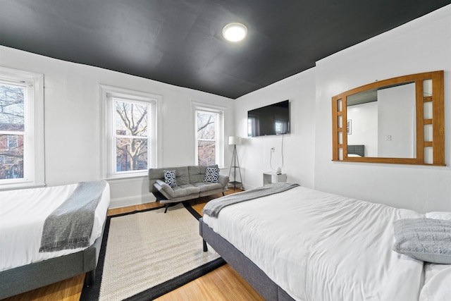 bedroom with multiple windows and hardwood / wood-style floors