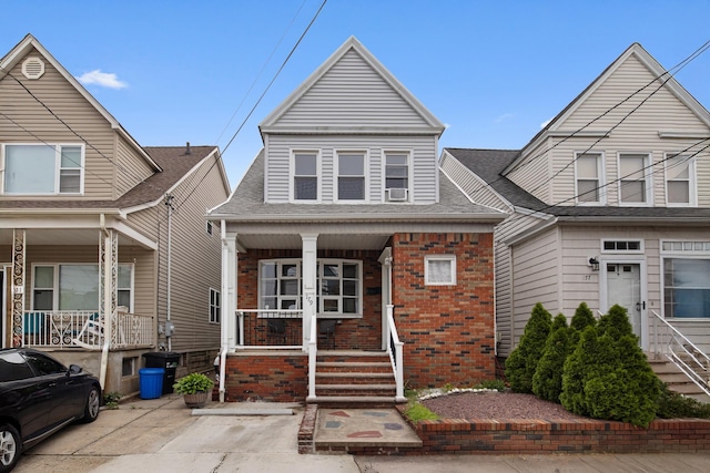 179 W 8th St, Bayonne, NJ 07002 - view of property with covered porch, brick siding, and roof with shingles