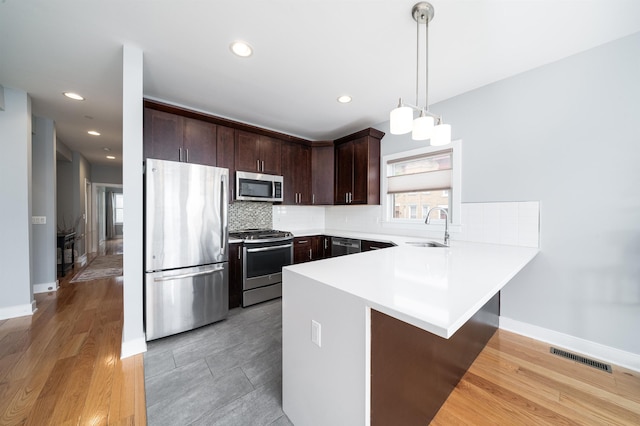 31 Ravine Ave Unit 1, Jersey City, NJ 07307 - kitchen featuring stainless steel appliances, a sink, a peninsula, dark brown cabinets, and light countertops
