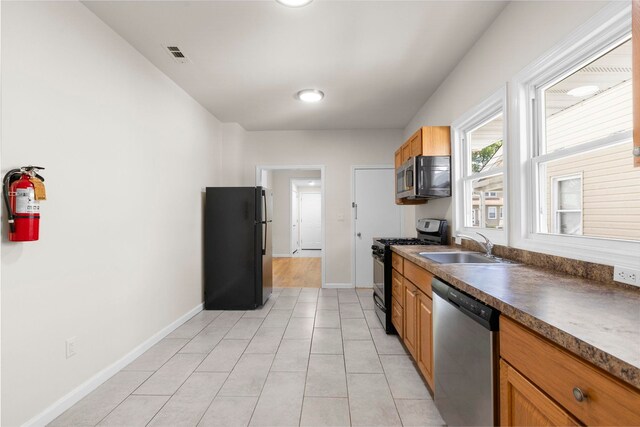 195 Stanley Pl, Hackensack, NJ 07601 - kitchen with stainless steel appliances, dark countertops, light tile patterned floors, and brown cabinetry