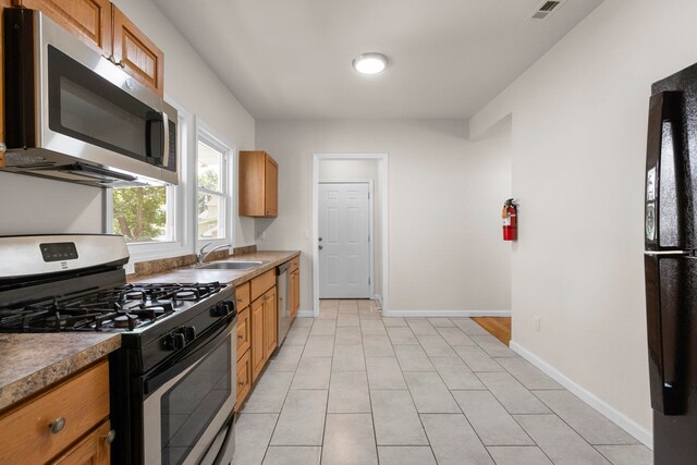 195 Stanley Pl, Hackensack, NJ 07601 - kitchen featuring appliances with stainless steel finishes, brown cabinetry, and light tile patterned floors