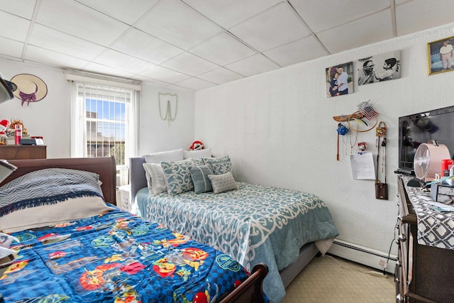 bedroom with a paneled ceiling and baseboard heating