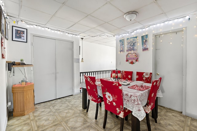 dining area featuring tile patterned floors and a drop ceiling