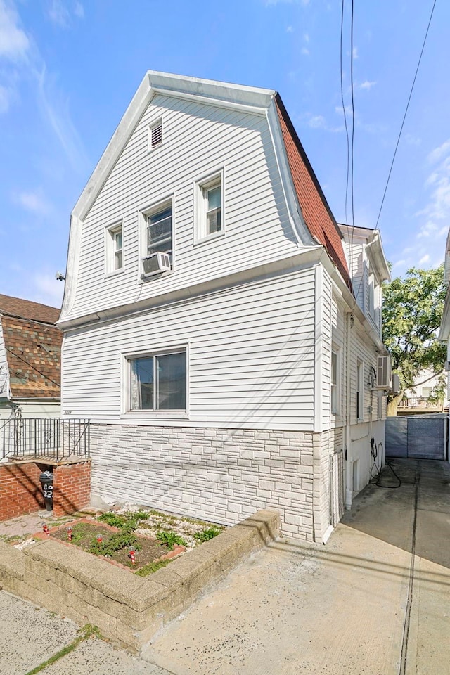 1224 80th St, North Bergen, NJ 07047 - view of property exterior featuring stone siding, cooling unit, and a gambrel roof