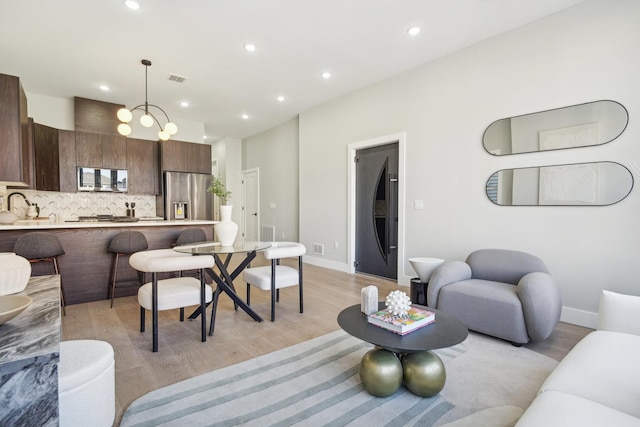 living room with light hardwood / wood-style flooring, a notable chandelier, and sink