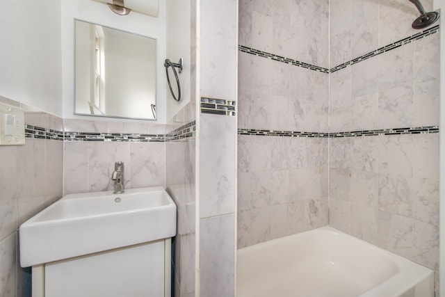 bathroom featuring vanity, tiled shower / bath combo, and tile walls