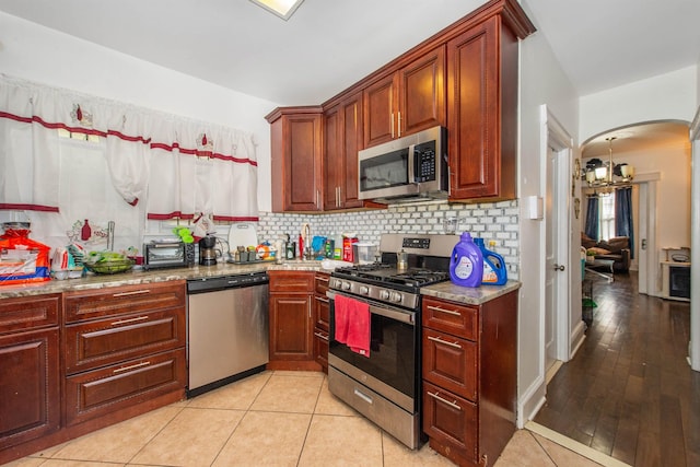 kitchen with light stone counters, backsplash, light tile patterned floors, and appliances with stainless steel finishes