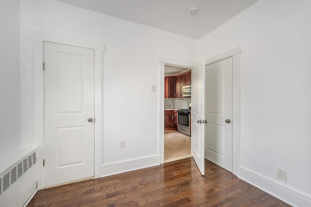 unfurnished room featuring dark hardwood / wood-style floors and radiator heating unit