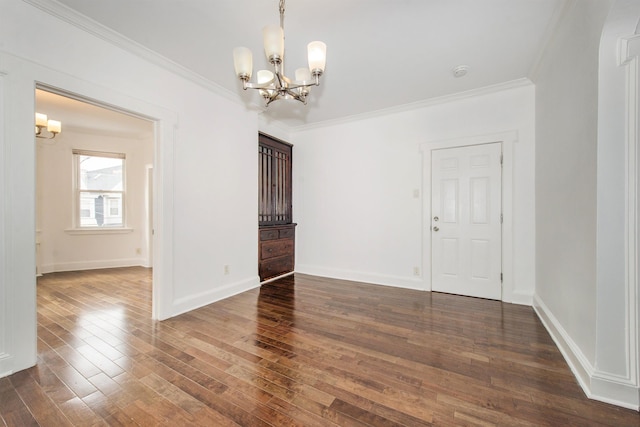 spare room with an inviting chandelier, dark hardwood / wood-style flooring, and crown molding