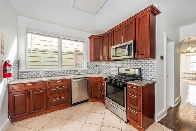 kitchen with light stone counters, appliances with stainless steel finishes, sink, and tasteful backsplash