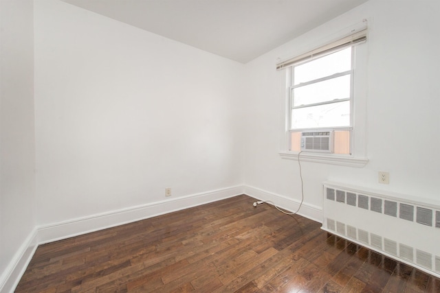 empty room with cooling unit, radiator, and dark hardwood / wood-style floors