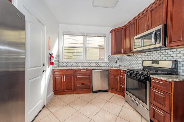 kitchen featuring sink, light tile patterned floors, appliances with stainless steel finishes, light stone countertops, and decorative backsplash