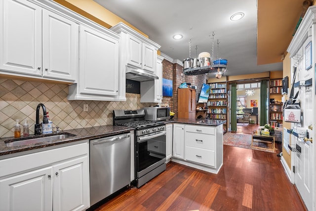 352 7th St Unit 3, Jersey City, NJ 07302 - kitchen featuring appliances with stainless steel finishes, a peninsula, dark wood-style flooring, white cabinetry, and decorative backsplash