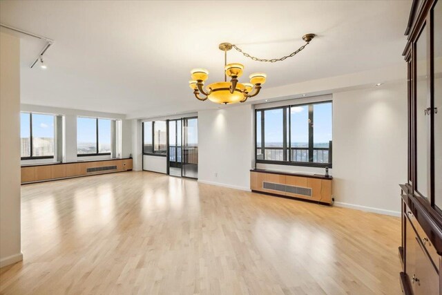 300 Winston Dr # 1822, Cliffside Park, NJ 07010 - unfurnished living room featuring a chandelier, radiator heating unit, and light wood finished floors