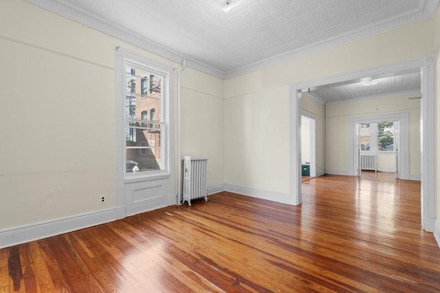 spare room with crown molding, wood-type flooring, and radiator heating unit