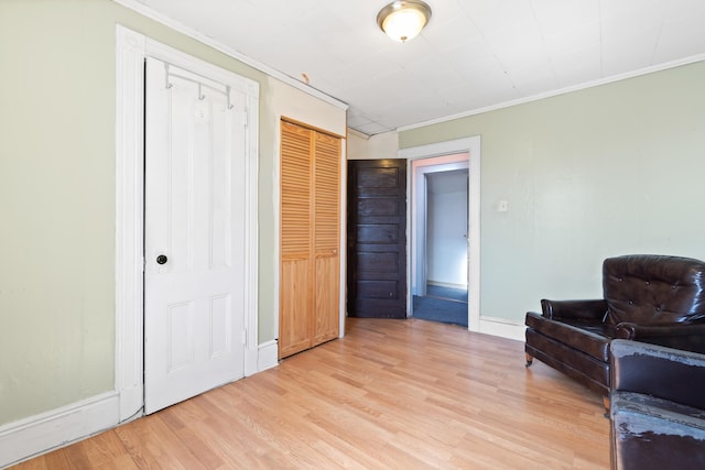 sitting room featuring light wood-type flooring, baseboards, and crown molding