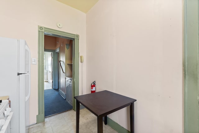 hallway with light colored carpet and light tile patterned floors