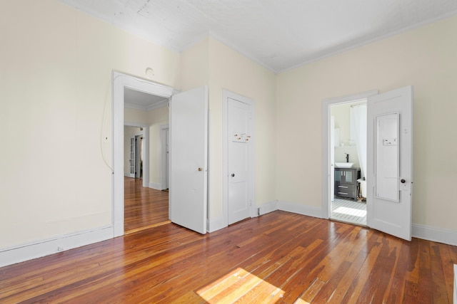 unfurnished bedroom with hardwood / wood-style floors, baseboards, and crown molding