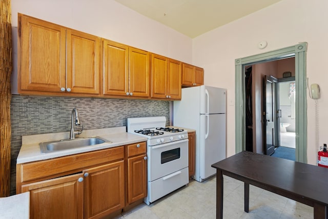 kitchen featuring white appliances, a sink, light countertops, and brown cabinetry