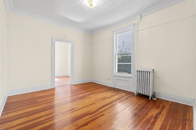 spare room with crown molding, hardwood / wood-style flooring, radiator, and baseboards