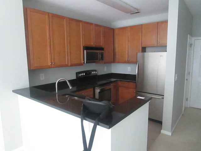 26 Ave At Port Imperial Unit 212, West New York, NJ 07093 - kitchen with appliances with stainless steel finishes, a peninsula, dark countertops, and brown cabinetry