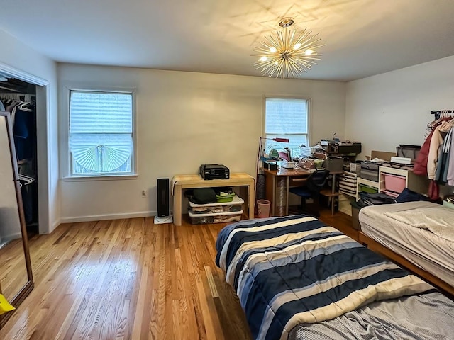 bedroom with a chandelier, multiple windows, a closet, and light hardwood / wood-style flooring