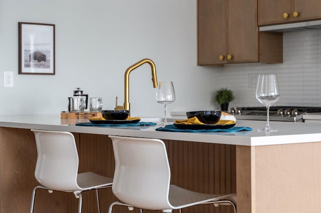 kitchen featuring a breakfast bar area, exhaust hood, and backsplash