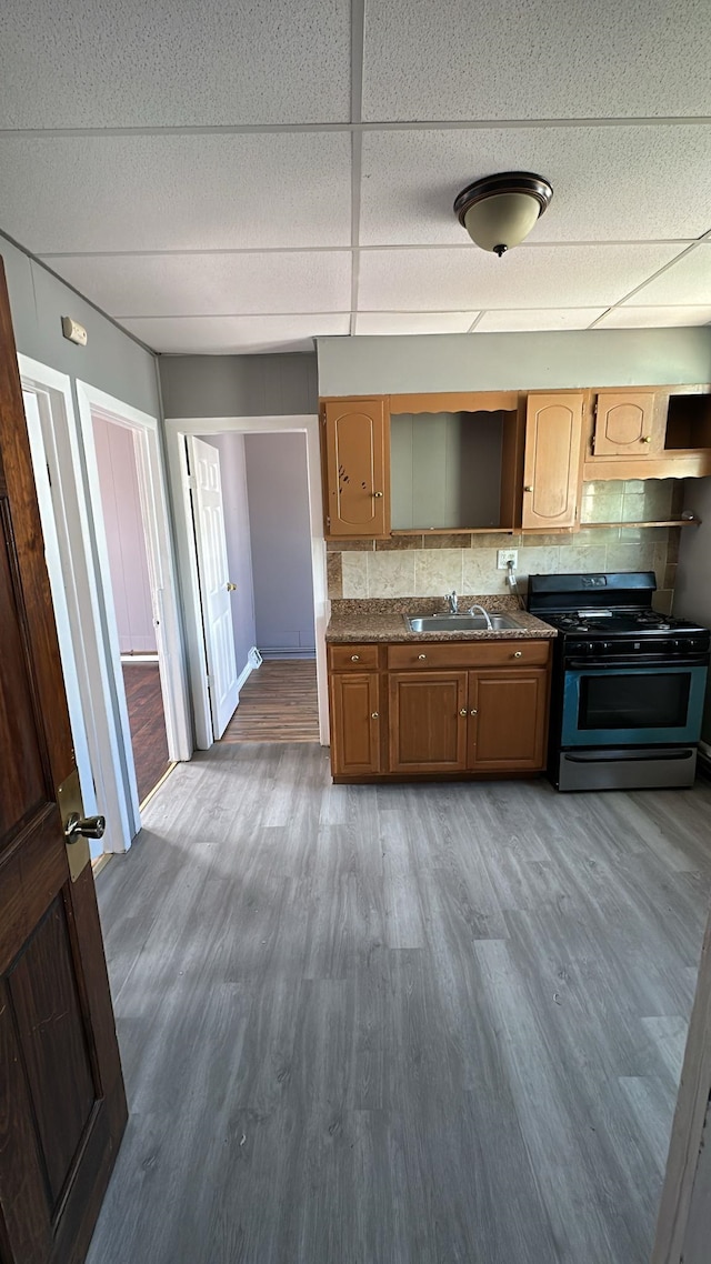79 W 18th St, Bayonne, NJ 07002 - kitchen with black range with gas stovetop, wood finished floors, tasteful backsplash, a drop ceiling, and dark stone counters