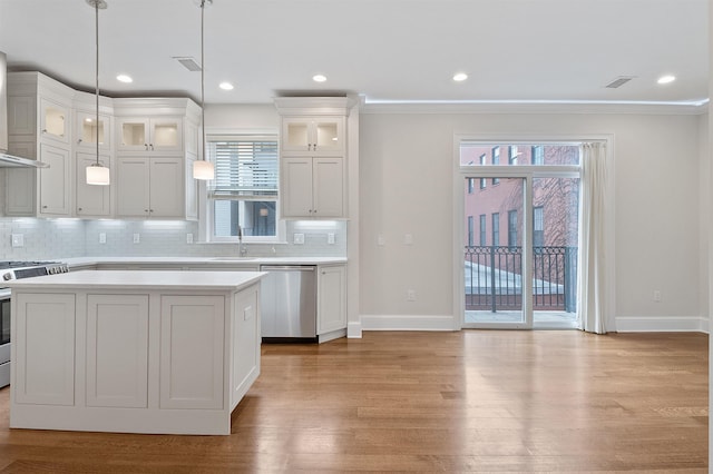 kitchen featuring appliances with stainless steel finishes, pendant lighting, decorative backsplash, sink, and white cabinetry