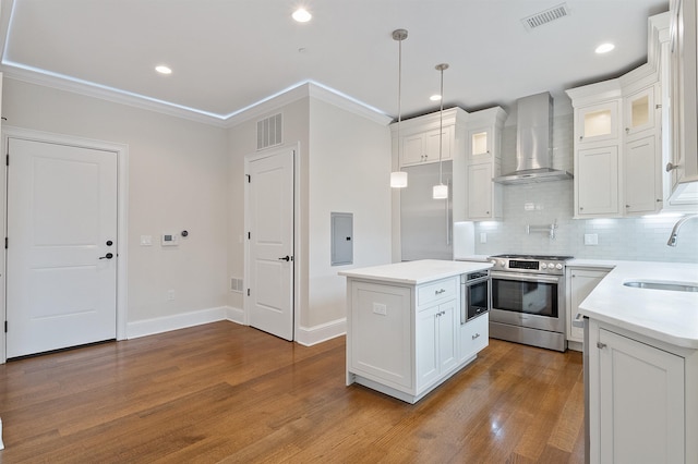 kitchen with white cabinets, stainless steel gas range, a kitchen island, and wall chimney exhaust hood