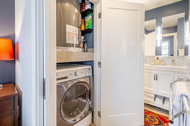 clothes washing area featuring washer / dryer, water heater, tile patterned floors, and laundry area