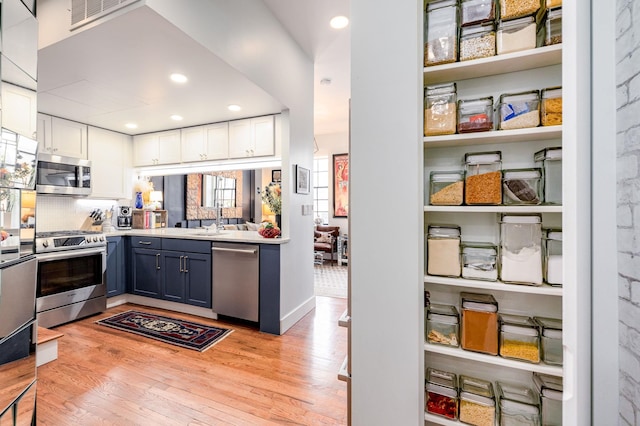 kitchen featuring visible vents, a sink, white cabinets, light wood-style floors, and appliances with stainless steel finishes