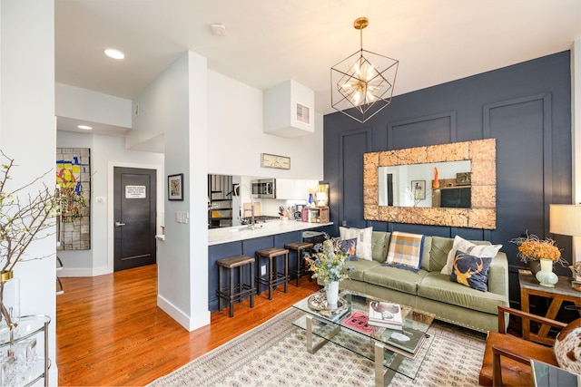 living area featuring visible vents, wood finished floors, recessed lighting, an inviting chandelier, and baseboards