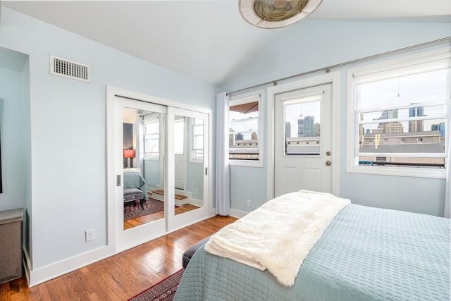 bedroom with visible vents, lofted ceiling, baseboards, and wood finished floors