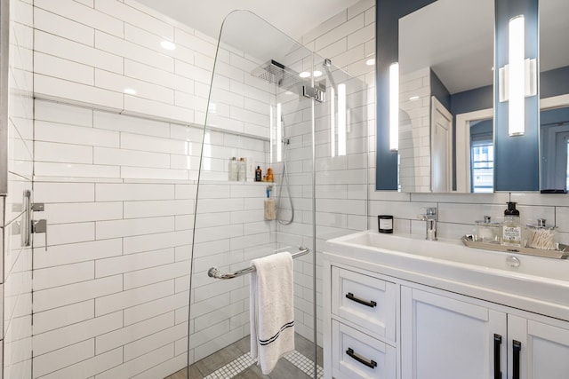 bathroom with tile walls, tiled shower, vanity, and tasteful backsplash