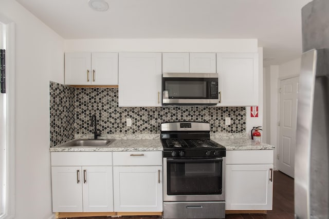 23 Westervelt Pl, Jersey City, NJ 07304 - kitchen featuring tasteful backsplash, white cabinets, a sink, light stone countertops, and stainless steel appliances