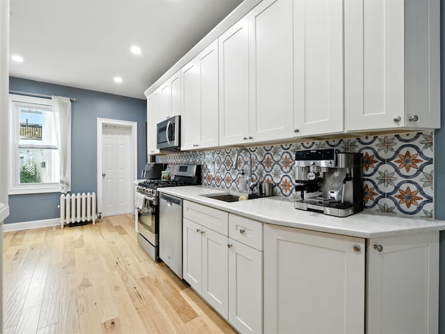 75 Reservoir Ave, Jersey City, NJ 07307 - kitchen with radiator, appliances with stainless steel finishes, tasteful backsplash, white cabinets, and recessed lighting