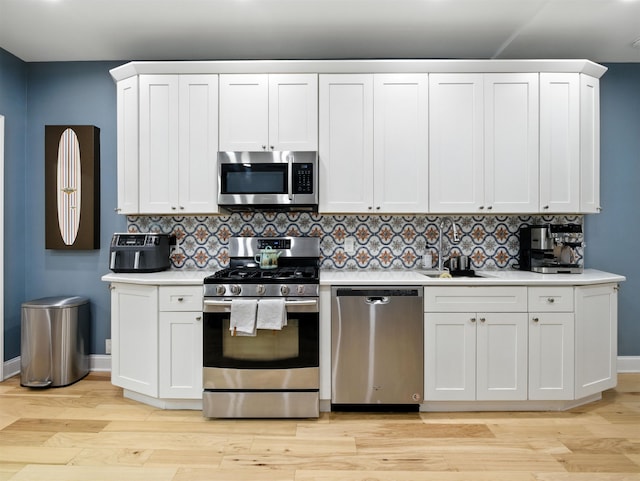 75 Reservoir Ave, Jersey City, NJ 07307 - kitchen with stainless steel appliances, light countertops, light wood-type flooring, decorative backsplash, and white cabinets