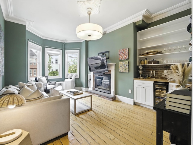 75 Reservoir Ave, Jersey City, NJ 07307 - living room with wet bar, ornamental molding, wine cooler, light wood-type flooring, and a glass covered fireplace