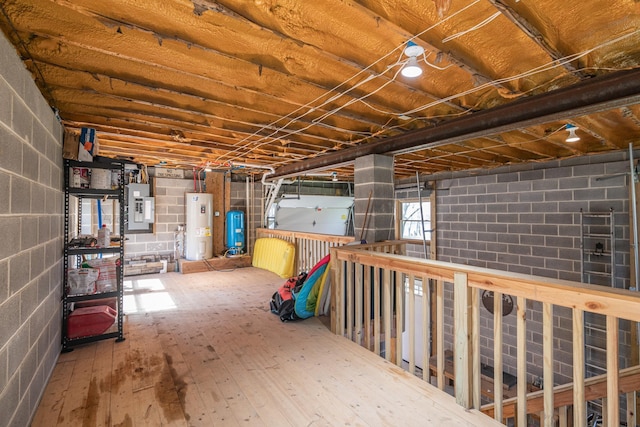 basement featuring electric panel, water heater, and hardwood / wood-style flooring