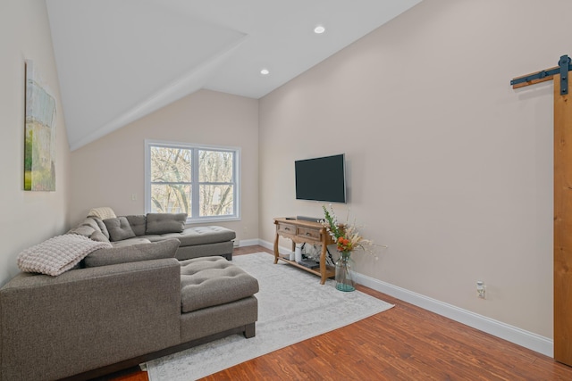 living room featuring lofted ceiling, a barn door, and wood-type flooring