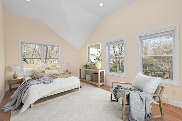 bedroom with hardwood / wood-style flooring, a baseboard radiator, and vaulted ceiling