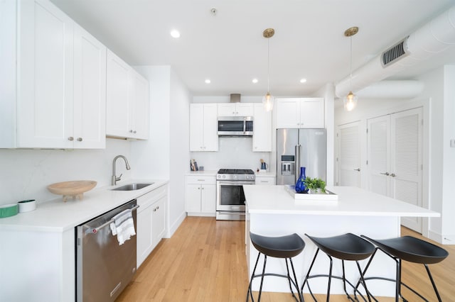 414 1st St Unit 5, Jersey City, NJ 07302 - kitchen with appliances with stainless steel finishes, a kitchen breakfast bar, light wood-style flooring, white cabinetry, and recessed lighting