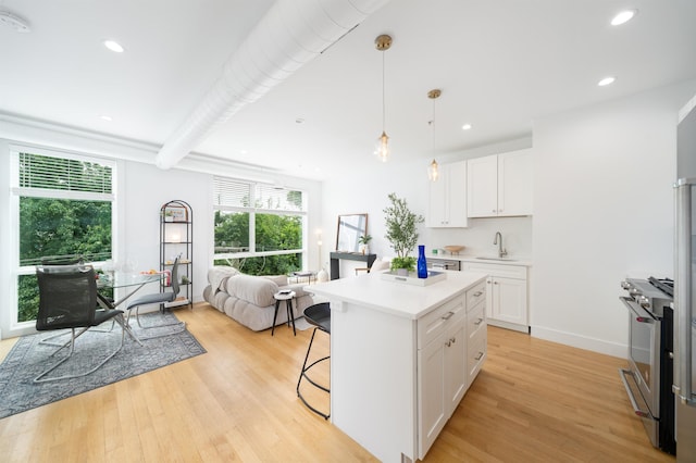 414 1st St Unit 5, Jersey City, NJ 07302 - kitchen with high end stainless steel range oven, open floor plan, a breakfast bar, white cabinets, and light wood-type flooring