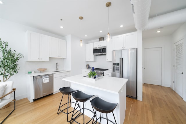 414 1st St Unit 5, Jersey City, NJ 07302 - kitchen featuring appliances with stainless steel finishes, light wood-style floors, a breakfast bar, white cabinetry, and a kitchen island