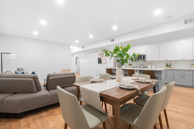 dining area featuring light wood-type flooring and sink