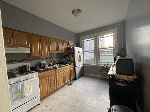 33 Clerk St, Jersey City, NJ 07305 - kitchen with under cabinet range hood, white range with gas stovetop, freestanding refrigerator, and light tile patterned floors